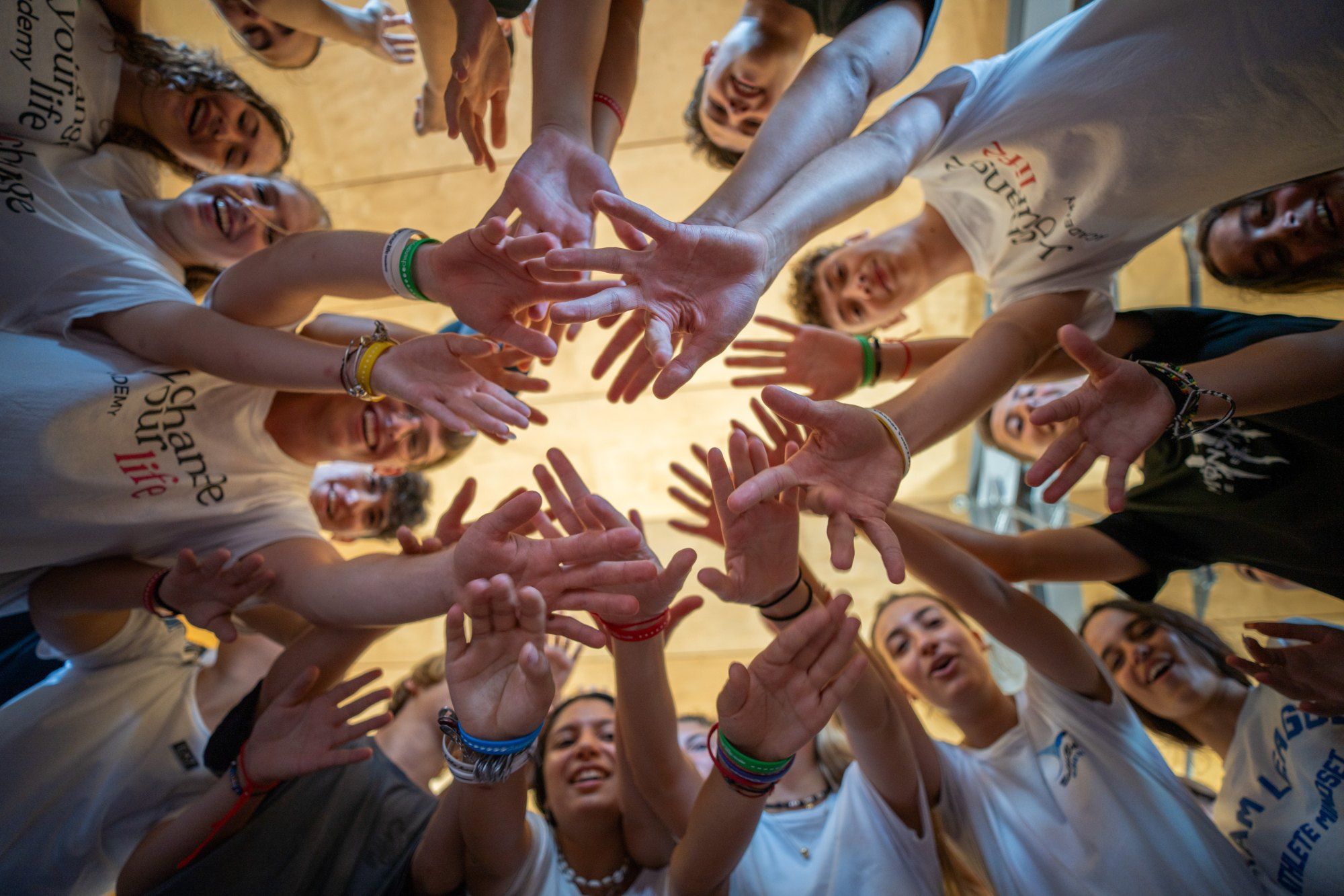 Smiling young people join hands in a circle during a Change Your Life experience