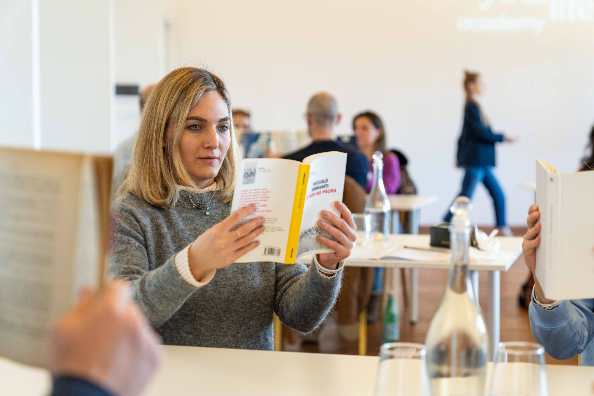 Una partecipante sorride leggendo un libro durante Change Your Life Leadership
